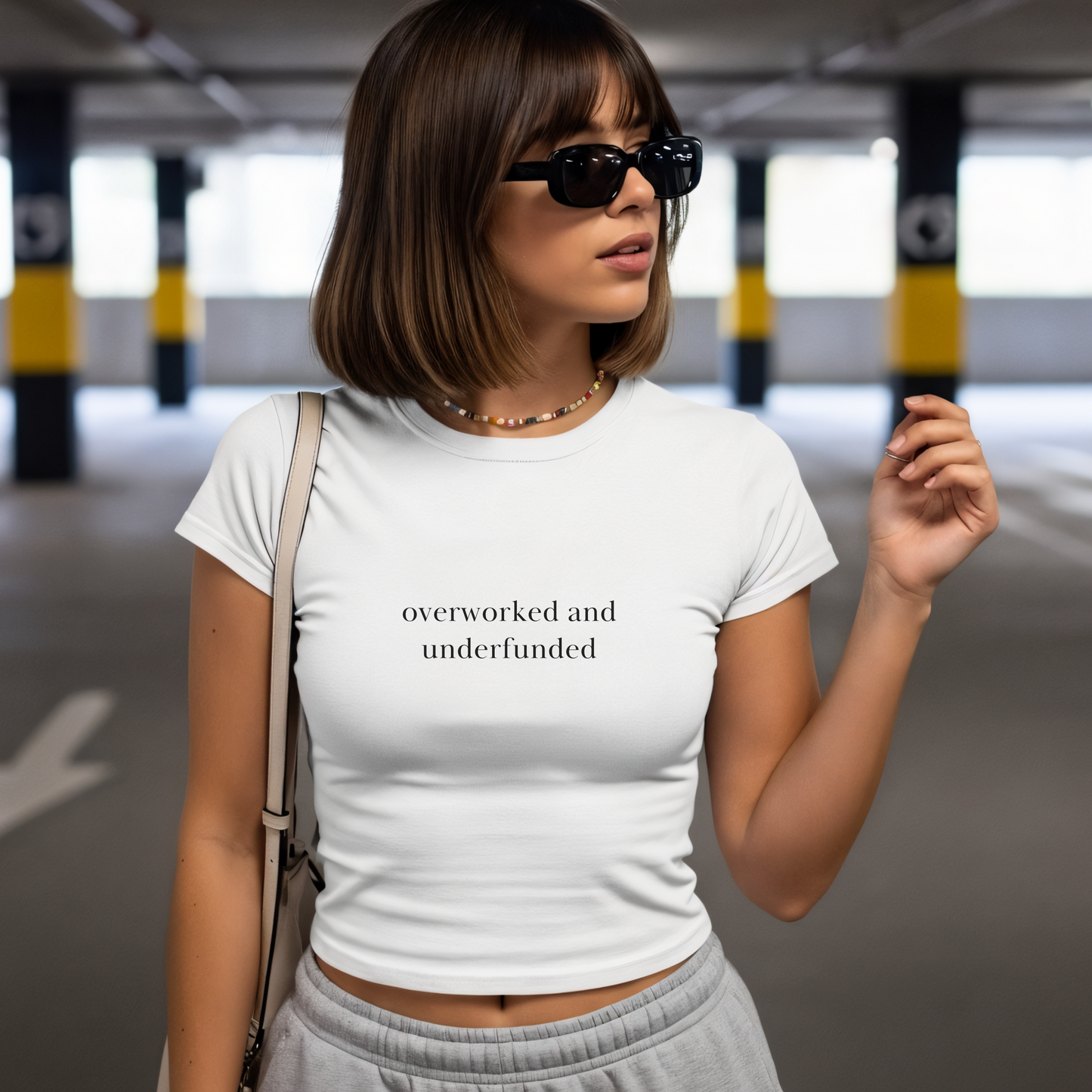 Shirtgeist Overworked and Underfunded Baby Tee — front view on model